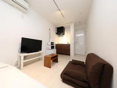 a living room with a couch and a flat screen tv at - KOMA Hotel- \u6d45\u8349\u99c5\u5f92\u6b696\u5206 \u7bc9\u6d45\u3067Wi-Fi\u4ed8\u304d \u5bb6\u5177\u5bb6\u96fb\u5145\u5b9f in Tokyo