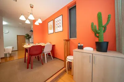 a dining room with orange walls and a table with a cactus at \u677e\u304c\u8c37\u30a2\u30d1\u30fc\u30c8\u30e1\u30f3\u30c8301 in Tokyo