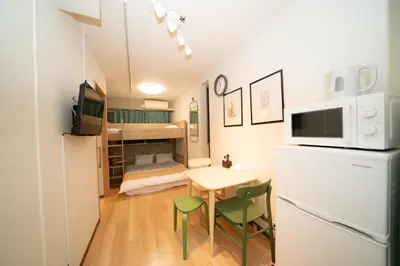 a small room with a table and a refrigerator and a bed at \u677e\u304c\u8c37\u30a2\u30d1\u30fc\u30c8\u30e1\u30f3\u30c8101 in Tokyo