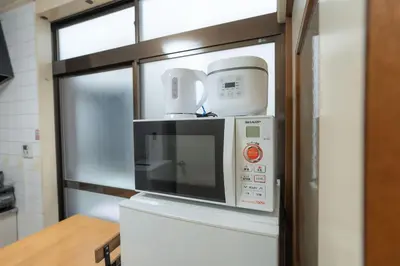 a microwave oven sitting on top of a refrigerator at Kamitagata House in Nakano Sleeps 7Just Steps from Araiyakushi-Mae Station in Tokyo