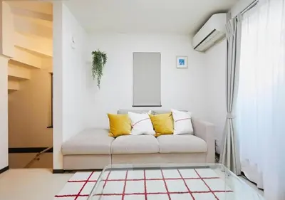 a white living room with a couch with yellow pillows at Naka HOUSE in Tokyo