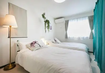 two beds in a room with a lamp and a window at Naka HOUSE in Tokyo