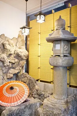 a stone lantern and an umbrella in front of a building at Business Hotel Yamashiro in Tokyo