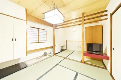 a living room with a television and wooden ceilings at Business Hotel Yamashiro in Tokyo