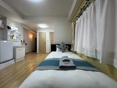 a bedroom with a large bed and a kitchen at nestay apartment tokyo kagurazaka in Tokyo