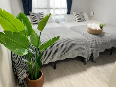 a room with two beds and a plant at COMMA HOUSE Otsuka 3-1 in Tokyo