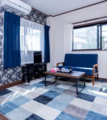 a living room with a blue couch and a table at Dain Hostel1 in Tokyo