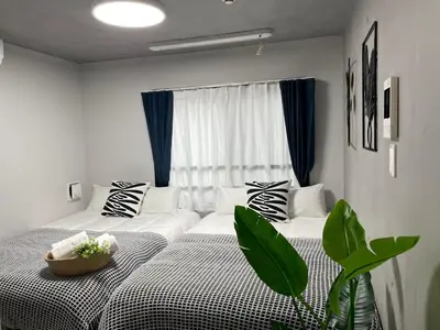 a bedroom with two beds with black and white pillows at COMMA HOUSE Otsuka 3-3 in Tokyo
