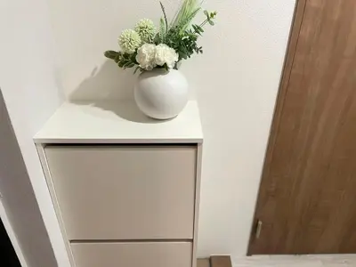 a white vase with flowers on top of a cabinet at COMMA HOUSE Otsuka 3-3 in Tokyo