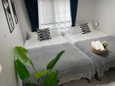two twin beds in a room with a window at COMMA HOUSE Otsuka 4-1 in Tokyo
