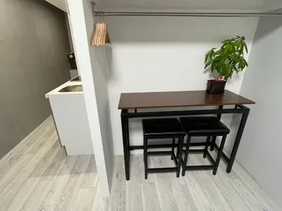 a table with two stools and a potted plant at COMMA HOUSE Otsuka 4-3 in Tokyo