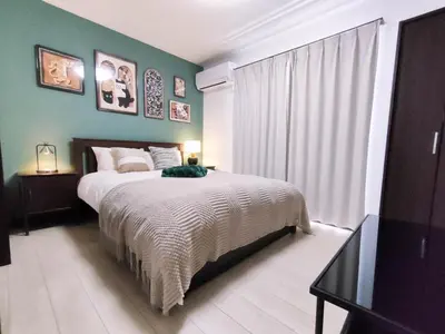 a bedroom with a bed and a green wall at \u6c60\u888b\u72ec\u7acb3\u5c42\u522b\u5885 5\u5ba41\u53851\u6d74\u5ba42\u536b\u751f\u95f4 \u6700\u592712\u4eba \u94f6\u5ea7\u65b0\u5bbf\u6d89\u8c37\u4e0a\u91ce\u4e1c\u4eac\u76f4\u901a in Tokyo
