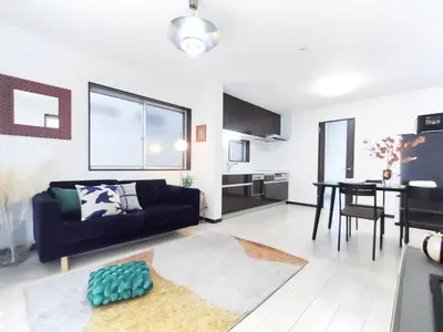 a living room with a black couch and a table at \u6c60\u888b\u72ec\u7acb3\u5c42\u522b\u5885 5\u5ba41\u53851\u6d74\u5ba42\u536b\u751f\u95f4 \u6700\u592712\u4eba \u94f6\u5ea7\u65b0\u5bbf\u6d89\u8c37\u4e0a\u91ce\u4e1c\u4eac\u76f4\u901a in Tokyo