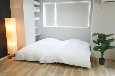 a white bed in a bedroom with a potted plant at Hotel TORAKEN in Tokyo