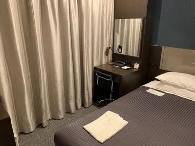 a hotel room with a bed and a desk and a mirror at Ochanomizu Inn in Tokyo
