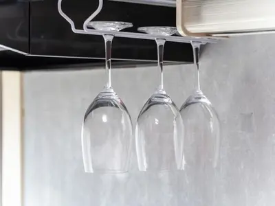 three wine glasses hanging from a rack in a kitchen at Shinjuku, 3min walk from Nishi-Shinjuku 5-chome Sta, 3min Shinjuku Sta Switch, Wi-Fi ,Pocketwi-Fi in Tokyo