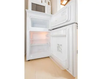 an empty refrigerator with its door open in a kitchen at Sakura Suite in Tokyo
