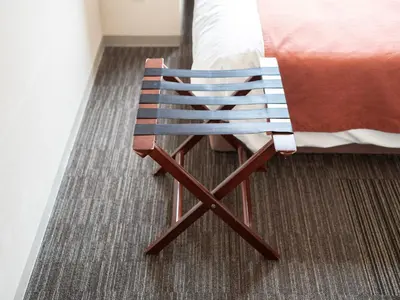 a wooden chair sitting next to a bed in a room at Super Hotel Premier Akasaka in Tokyo