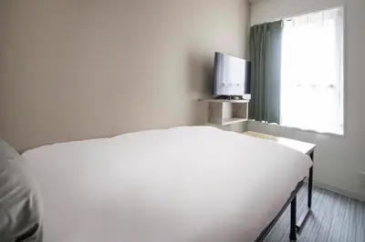 a bedroom with a white bed and a television at CH RESiDENCE \u65e9\u7a32\u7530\u9db4\u5dfb\u753a in Tokyo