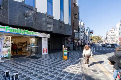 a woman walking down a sidewalk in a city at CH RESiDENCE \u65e9\u7a32\u7530\u9db4\u5dfb\u753a in Tokyo
