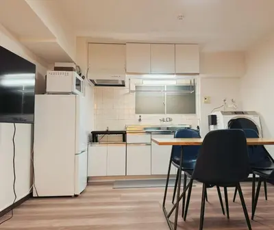 a kitchen with a table and chairs and a refrigerator at LoveTokyo Easy Access Nezu Sunset House \u6839\u6d25\u99c5\u5f92\u6b691\u5206 \u30a8\u30ec\u30d9\u30fc\u30bf\u30fc \u4e0a\u91ce \u8c37\u4e2d\u9280\u5ea7 \u6839\u6d25\u795e\u793e \u6771\u4eac\u5927\u5b66 \u65b0\u5bbf \u6e0b\u8c37 \u9280\u5ea7 \u7bc9\u5730 \u539f\u5bbf\u8fd1\u3044 in Tokyo
