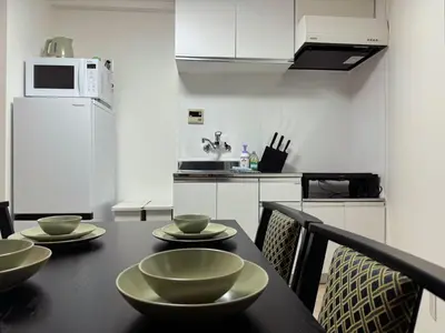 a kitchen with a black table with bowls on it at LoveTokyo Easy Access Nezu Sunset House \u6839\u6d25\u99c5\u5f92\u6b691\u5206 \u30a8\u30ec\u30d9\u30fc\u30bf\u30fc \u4e0a\u91ce \u8c37\u4e2d\u9280\u5ea7 \u6839\u6d25\u795e\u793e \u6771\u4eac\u5927\u5b66 \u65b0\u5bbf \u6e0b\u8c37 \u9280\u5ea7 \u7bc9\u5730 \u539f\u5bbf\u8fd1\u3044 in Tokyo