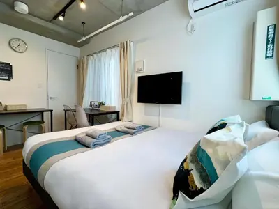 a bedroom with a large bed and a flat screen tv at nestay inn tokyo skytree in Tokyo