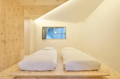 two beds in a white room with a window at SHORTsuido in Tokyo