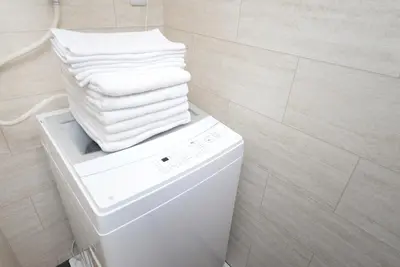 a stack of towels on top of a washing machine in a bathroom at Shinjuku NY House 301 in Tokyo