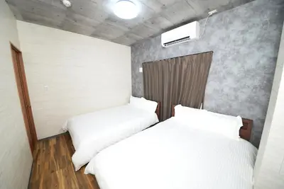 two beds in a small room with white sheets at Shinjuku NY House 301 in Tokyo