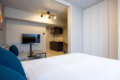 a bedroom with a white bed and a living room at MAT Ryogoku in Tokyo