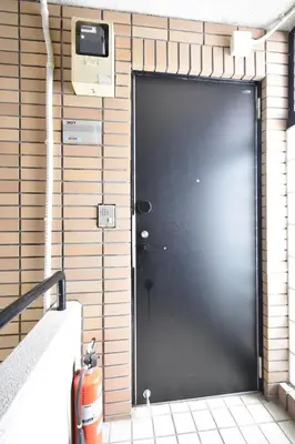 a black door on a brick wall with a television at Solana Roppongi in Tokyo