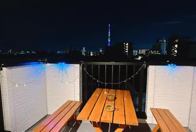 a wooden picnic table on a balcony at night at \u6771\u4eac\u30b9\u30ab\u30a4\u30c4\u30ea\u30fc\u30cf\u30a6\u30b9JoY in Tokyo