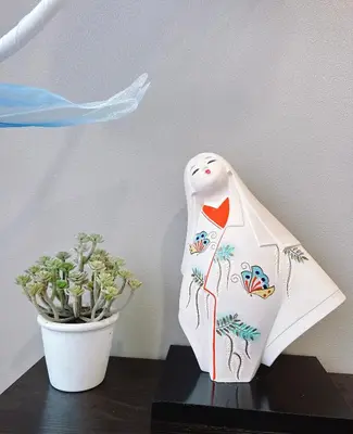 a white vase sitting on a table next to a plant at \u6771\u4eac\u30b9\u30ab\u30a4\u30c4\u30ea\u30fc\u30cf\u30a6\u30b9JoY in Tokyo