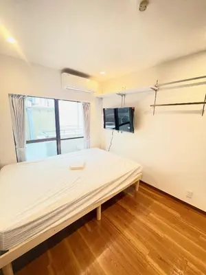 a bedroom with a bed and a tv on the wall at NEW fukuhana\u6771\u65b0\u5bbf in Tokyo