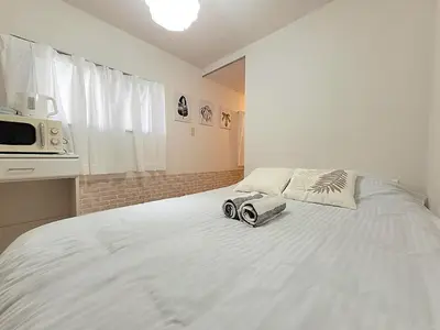 a bedroom with a white bed with two cameras on it at HUJI Shinjuku House in Tokyo