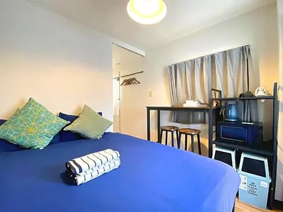 a bedroom with a blue bed and a tv at HUJI Shinjuku House in Tokyo