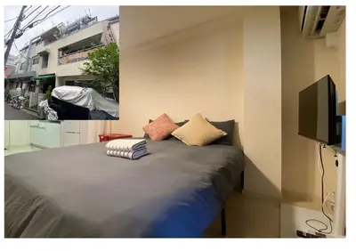a bedroom with a bed with pillows and a tv at Liberty Shinjuku House in Tokyo