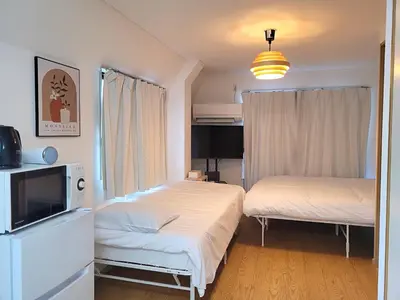 a bedroom with two beds and a tv at Liberty Shinjuku House in Tokyo