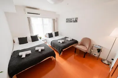 a room with two beds and a chair in it at Shinjuku luxury Apart ment 2 minutes from Higashi-Shinjuku in Tokyo