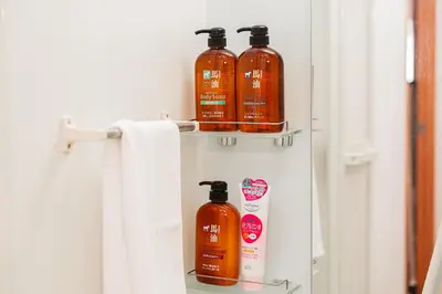 a bathroom with three bottles of shampoo and a towel at Shinjuku luxury Apart ment 2 minutes from Higashi-Shinjuku in Tokyo