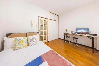 a bedroom with a bed and a desk with chairs at residencematsubara in Tokyo