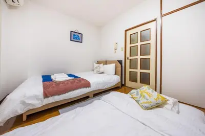 two beds in a room with white walls and wooden floors at residencematsubara in Tokyo