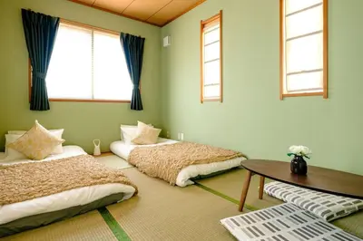 a bedroom with two beds and a table and windows at Haresora Mukojima Ikken House in Tokyo