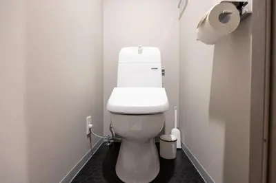 a white toilet in a bathroom with a roll of toilet paper at \u30a6\u30a7\u30eb\u30b9\u30af\u30a8\u30a2\u30a4\u30ba\u30e0\u6c60\u888b\u30a6\u30a7\u30b9\u30c8 in Tokyo