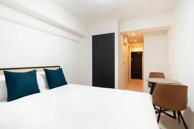 a bedroom with a white bed and a table and chairs at \u30eb\u30af\u30ec\u897f\u65b0\u5bbf in Tokyo