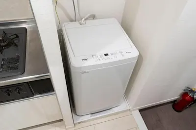 a white washing machine in a corner of a kitchen at \u30eb\u30af\u30ec\u897f\u65b0\u5bbf in Tokyo