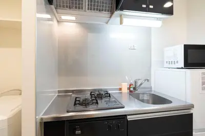 a kitchen with a stove and a sink and a microwave at \u30eb\u30af\u30ec\u897f\u65b0\u5bbf in Tokyo