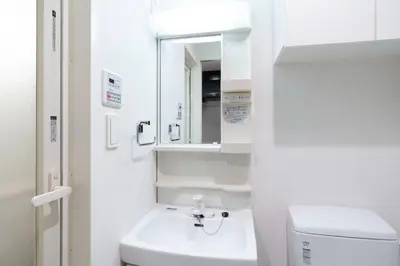 a white bathroom with a sink and a mirror at \u30eb\u30af\u30ec\u897f\u65b0\u5bbf in Tokyo