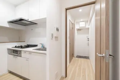 a kitchen with white cabinets and a sink and a door at \u30b0\u30ed\u30fc\u30d9\u30eb \u30b6 \u30af\u30ec\u30b9\u84b2\u7530 in Tokyo